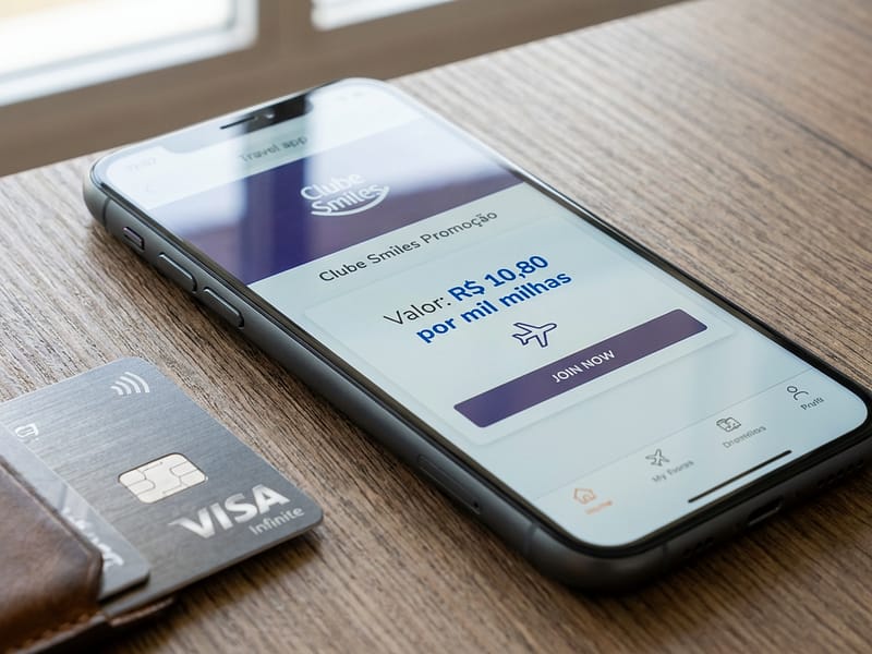 Cartão de crédito ao lado de um celular mostrando a promoção do Clube Smiles, com destaque para o valor do milheiro a R$ 10,80